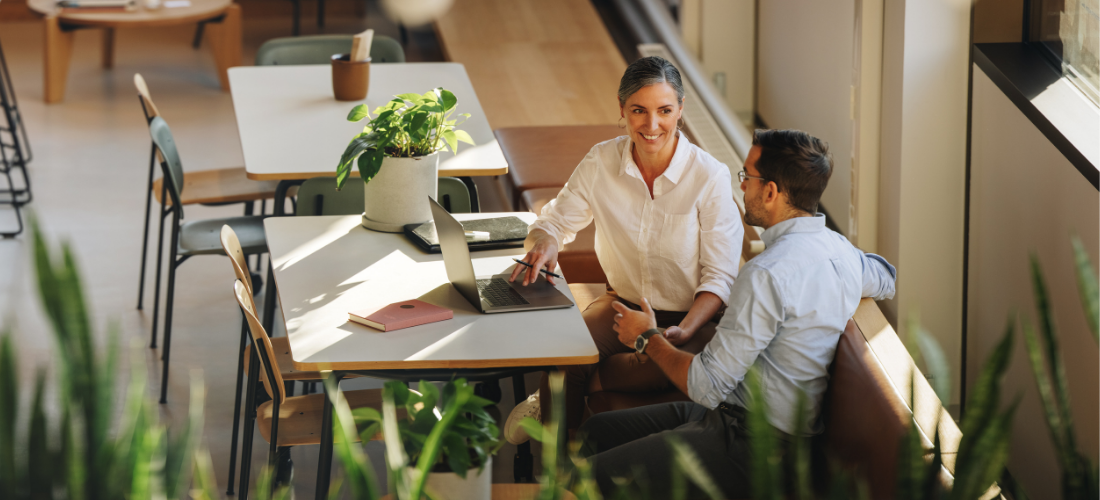Two people sitting at a table with a laptop