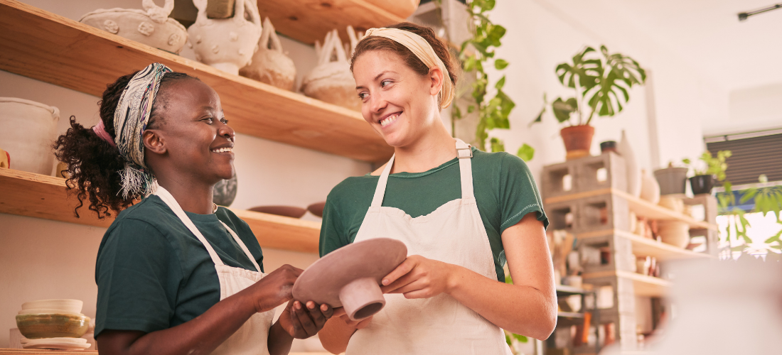Two women in a pottery studio holding a piece of pottery 